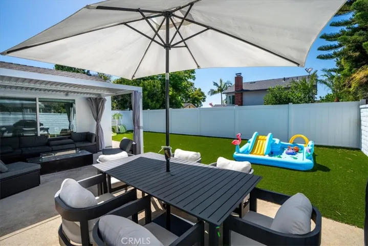 Backyard dining area with table, umbrella, and lawn space for entertaining