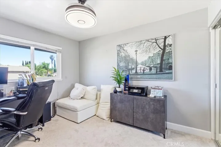 Secondary living area or office space with sectional sofa and large window.