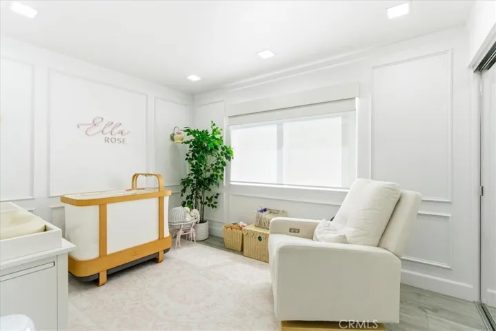 Bright nursery or sitting area with natural light from large window and light-colored furnishings.