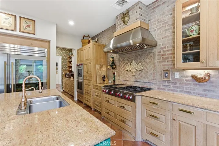 Professional-grade cooking appliances, custom brick detailing, and abundant workspace create a kitchen designed to inspire culinary creativity.