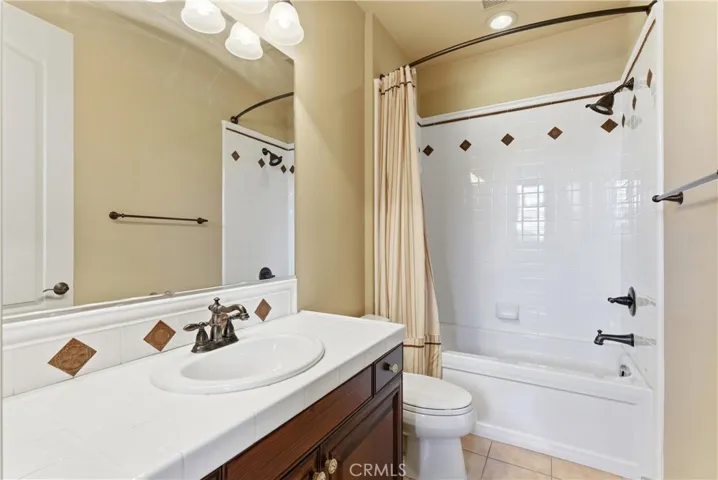 Bathroom with decorative tile accents, tub/shower combination, and generous counter space.