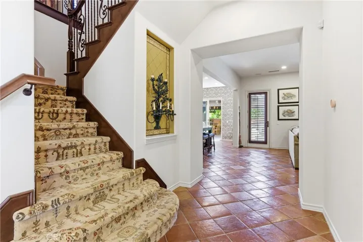 Inviting entry hall highlighted by Saltillo tile flooring, custom staircase, and architectural details.