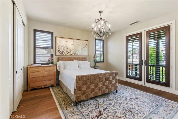 Spacious bedroom with French doors opening to a private balcony and plantation shutters throughout.