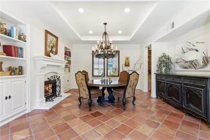 The formal dining room blends elegance and comfort with terracotta flooring, built-in cabinetry, a fireplace, and abundant natural light.