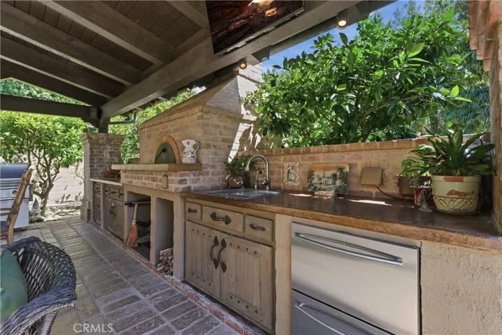 Custom outdoor kitchen complete with Mugnaini pizza oven, BBQ grill, sink, refrigeration, and extensive prep space.