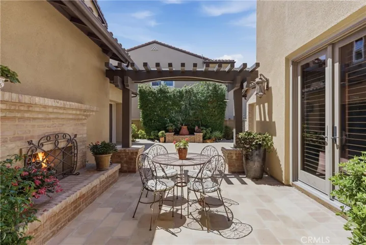 A private courtyard retreat featuring a covered pergola, outdoor fireplace, and multiple seating areas designed for year-round enjoyment.