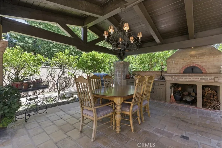 Covered outdoor pavilion featuring a custom wood ceiling, chandelier lighting, and built-in dining area.