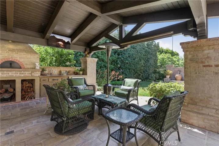 Resort-inspired outdoor living room with seating area, built-in fireplace, and views of the lush backyard.