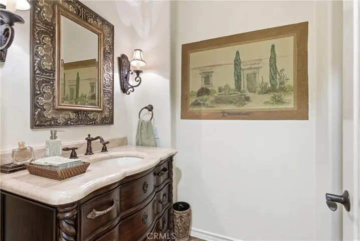 Elegant powder room featuring a furniture-style vanity, stone countertop, and designer fixtures.