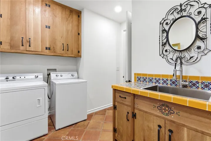 laundry room with custom cabinetry, decorative tile accents, and utility sink.