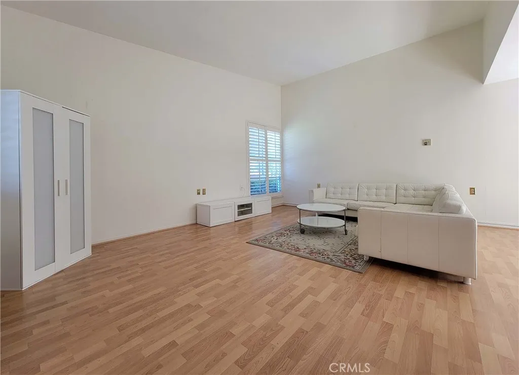 Large living room with vaulted ceiling, laminate floors and an extra window.