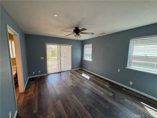 Primary bedroom with slider to back yard, ceiling fan and beautiful flooring