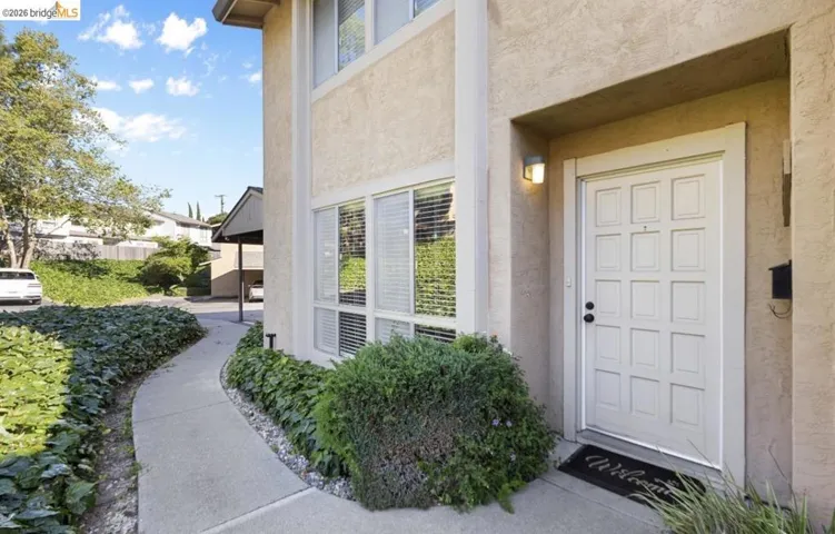 Stucco exterior with a paneled front door and an integrated exterior light fixture