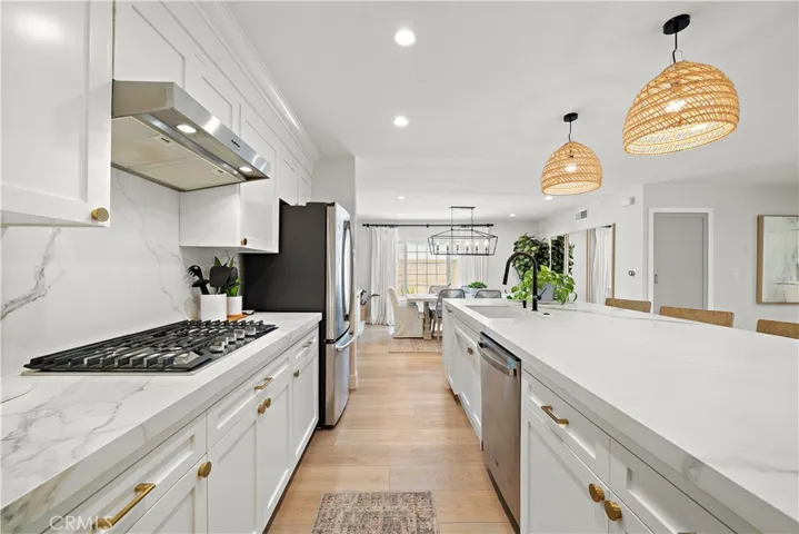 kitchen features gas cooktop, hood/vent, double ovens, microwave, dishwasher, and custom solid wood cabinetry