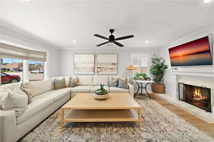 Beautiful formal living room with bay window, crown molding, fireplace, recessed lighting, and newer wide plank vinyl flooring