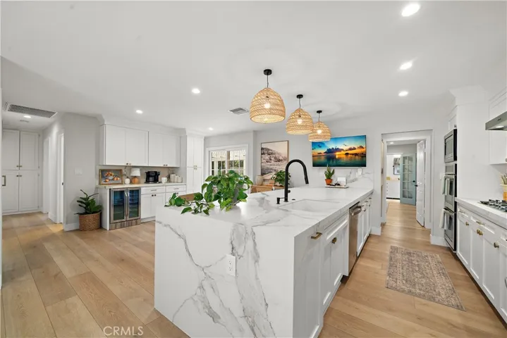 Beautifully remodeled kitchen has quartz countertops with waterfall, custom cabinetry, stainless appliances, breakfast bar