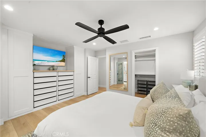 Primary suite has walk-in closet and entertainment center with built-in drawers, cabinetry, and shelving