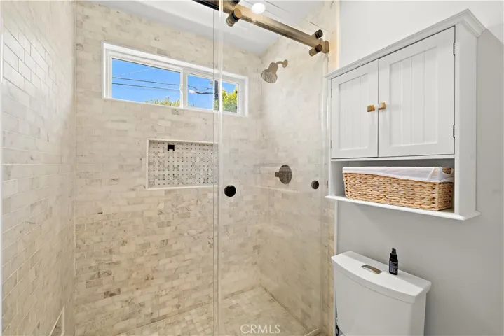 Pocket door opens to the walk-in shower with designer tile surround and clear glass enclosure