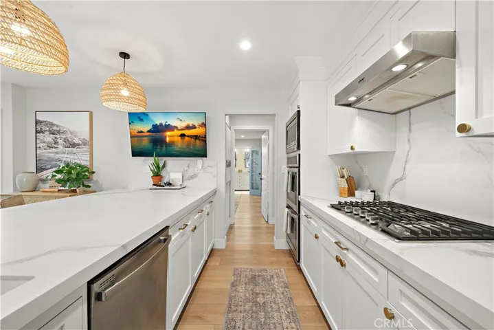 Quartz kitchen features gas cooktop, hood/vent, double ovens, microwave, dishwasher, and custom solid wood cabinetry