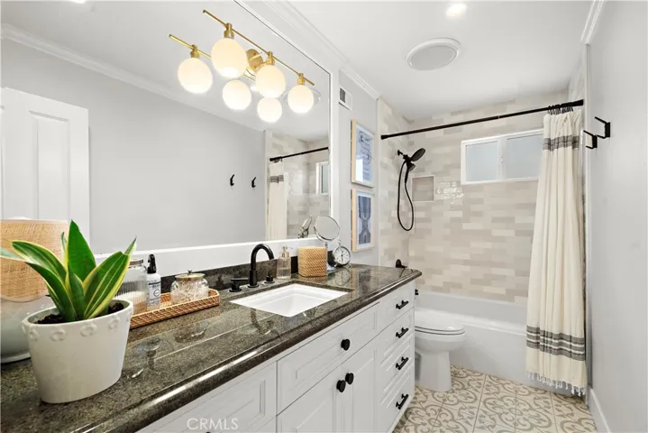 Guest Bathroom with granite countertop, chic title flooring, tub/shoer combo with subway tile surround