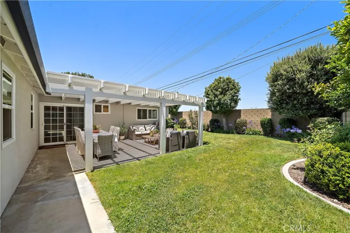 Covered patio, lush lawn, and beautiful gardens