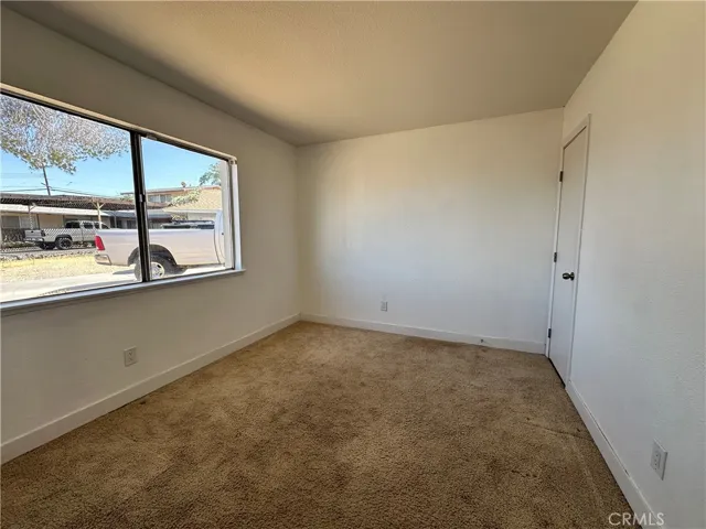 Primary Bedroom – Generously sized primary bedroom with expansive windows, soft carpeting, and ceiling fan, offering plenty of room for a variety of furniture arrangements.
