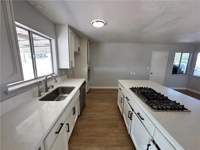 Kitchen – Updated kitchen showcasing quartz-style countertops, modern fixtures, stainless steel appliances, and a large island with built-in gas cooktop. Ample cabinetry provides plenty of storage.
