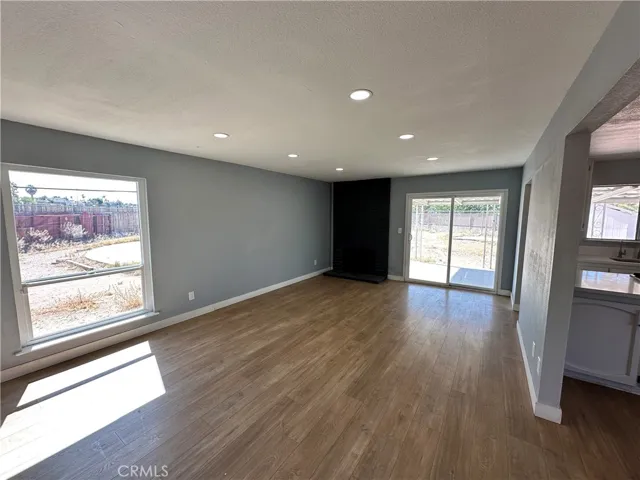 Living Room – Spacious living room featuring updated flooring, recessed lighting, a striking fireplace accent wall, and large windows that fill the space with natural light. Sliding glass doors provide easy access to the backyard patio.