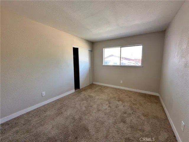 3rd Bedroom – Bright secondary bedroom featuring soft carpeting, neutral finishes, and a large window that brings in natural light throughout the day.