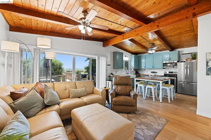 Open-concept living space featuring wood-finish flooring, exposed wood beam ceiling, and sliding glass doors to the exterior