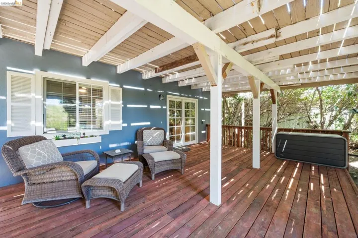Expansive outdoor deck featuring a slat-covered patio roof, wood flooring, and white support beams