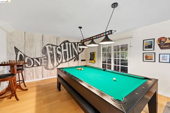 Recreation room featuring wood-finish flooring, a decorative accent wall, and a set of French doors