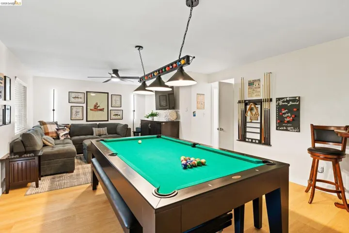 Recreational room featuring a billiard table with overhead lighting, wood-finish flooring, a ceiling fan, and a built-in wet bar