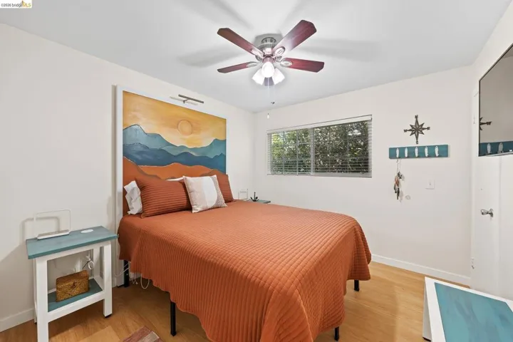 Bright interior room featuring wood-finish flooring and a window with horizontal blinds