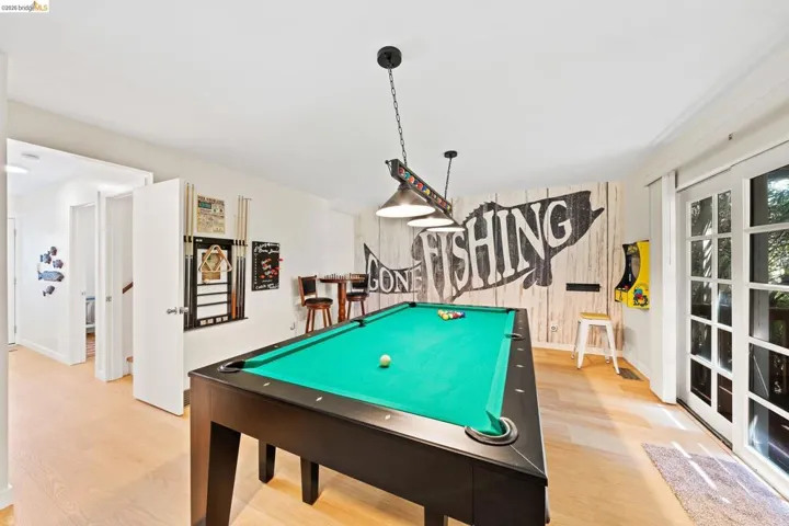 Recreation room featuring a pool table with pendant lighting, light wood-finish flooring, and French doors