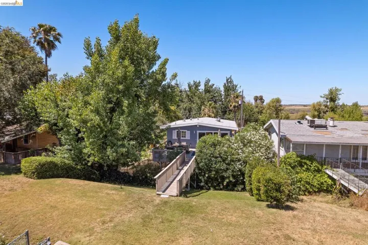 Elevated property featuring a light blue exterior, a spacious deck, and a long wooden walkway