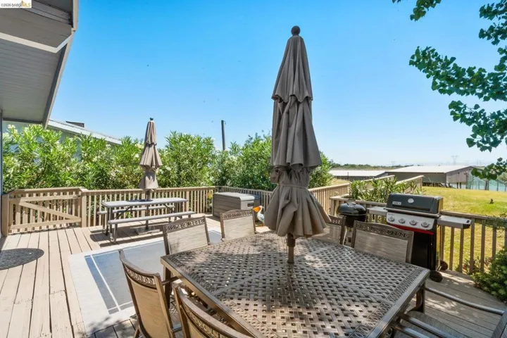 Expansive wood-finish deck with perimeter railing and two distinct patio umbrella placements