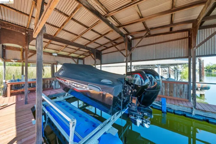 Covered boat dock featuring a corrugated metal roof, wood support beams, and a boat lift