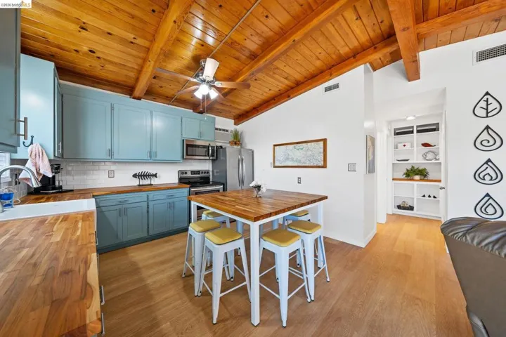 Kitchen featuring light blue cabinetry, wood-finish countertops, stainless steel appliances, and a subway tile backsplash