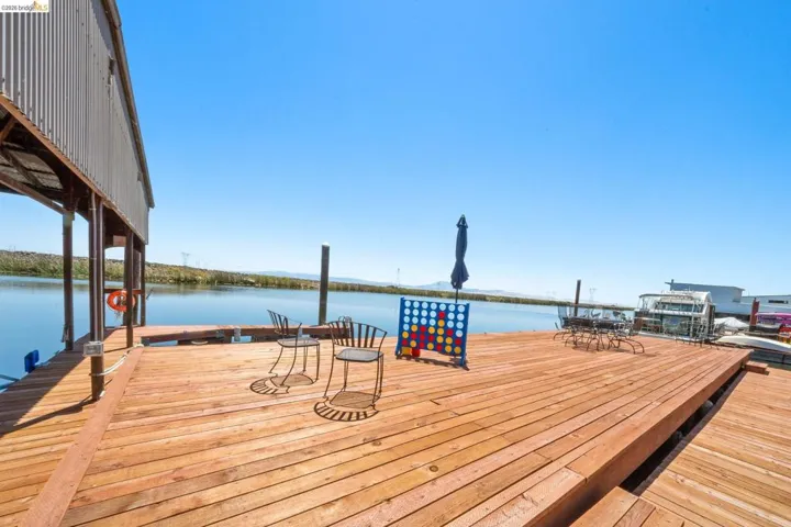 Expansive waterfront deck featuring natural wood planks, a covered boat dock, and direct water access