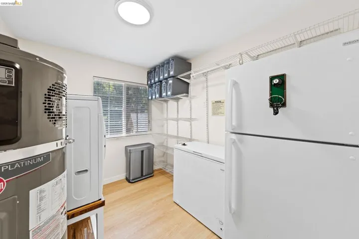 Utility space featuring wood-finish flooring, a double-pane window with blinds, and built-in wire shelving