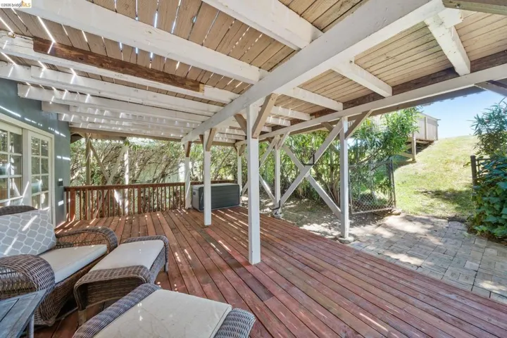 Expansive outdoor deck with a slatted wood pergola, rich wood-finish flooring, and white support beams