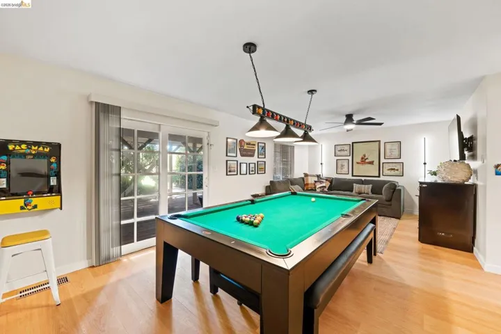 Open-concept recreation area featuring wood-finish flooring, a contemporary ceiling fan, and French-style glass doors