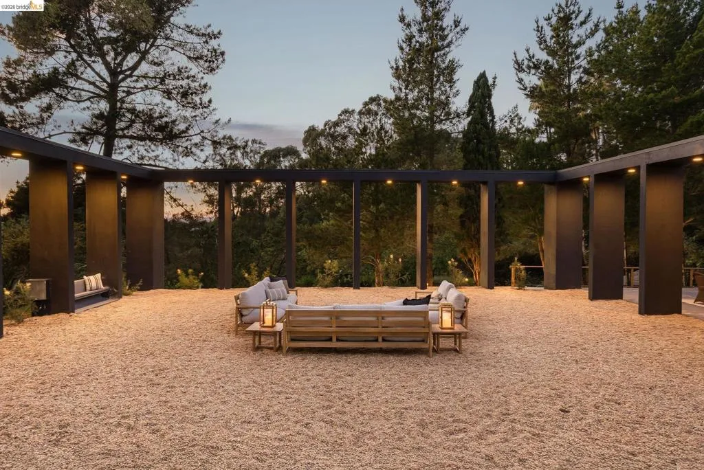 Expansive outdoor patio area featuring a light-colored gravel surface and a dark-toned pergola structure