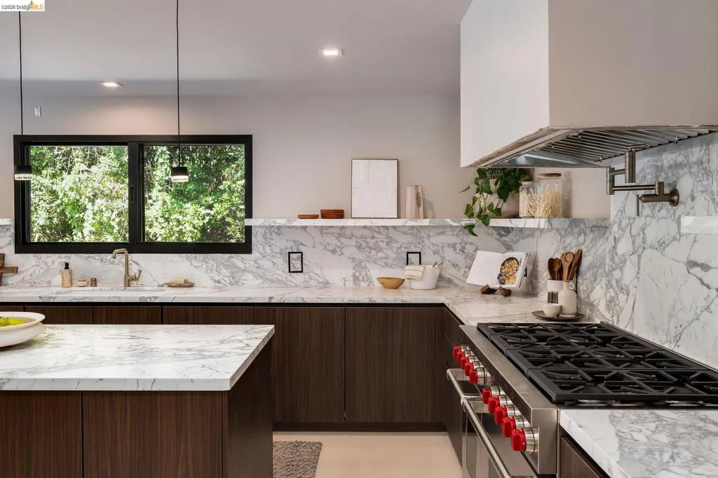 Gourmet kitchen featuring a built-in stainless steel range, marble countertops, dark wood-finish cabinetry, a pot filler, and recessed lighting