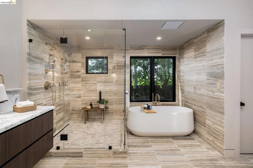 Spacious bathroom featuring a frameless glass shower enclosure, a freestanding soaking tub, and a floating vanity with a light-toned countertop
