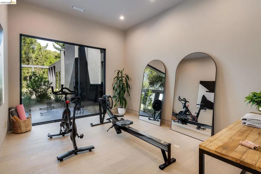 Dedicated fitness space featuring a full-height black-framed window, light wood-finish flooring, recessed lighting, and neutral wall tones