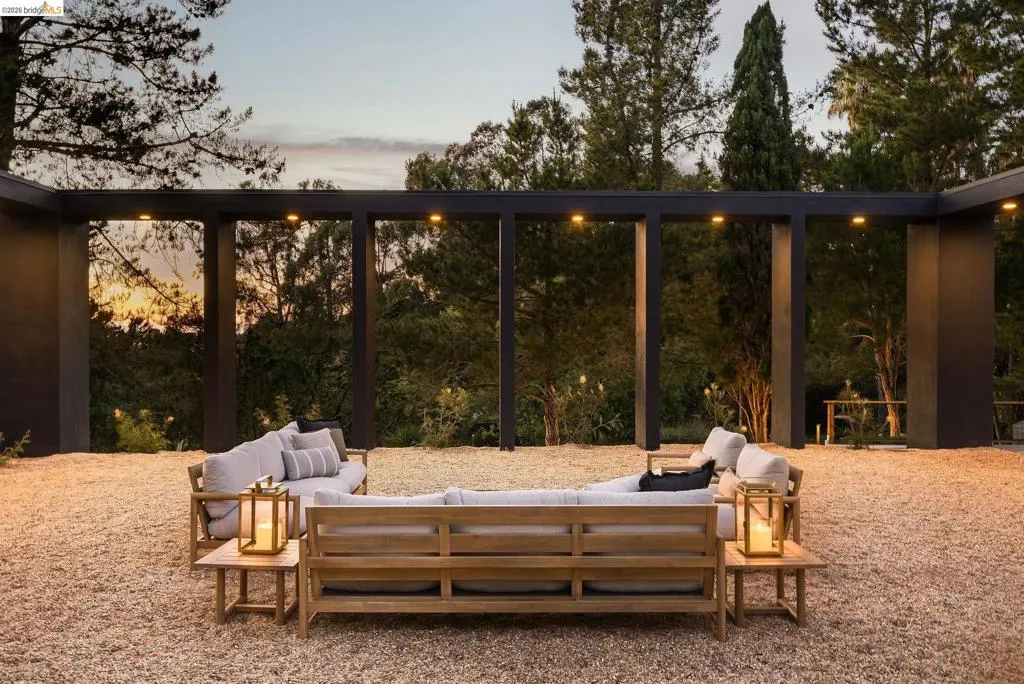 Outdoor living space featuring a dark-toned modern pergola structure with integrated downlighting
