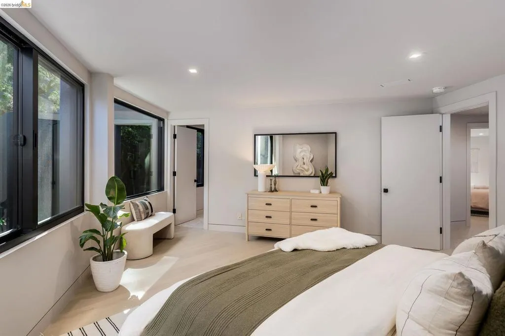 Spacious room featuring multiple large black-framed windows, light wood-finish flooring, recessed lighting, and white walls
