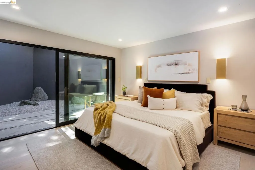 Light-toned flooring in a bedroom featuring a sliding glass door opening to a private outdoor space with gravel and stone elements